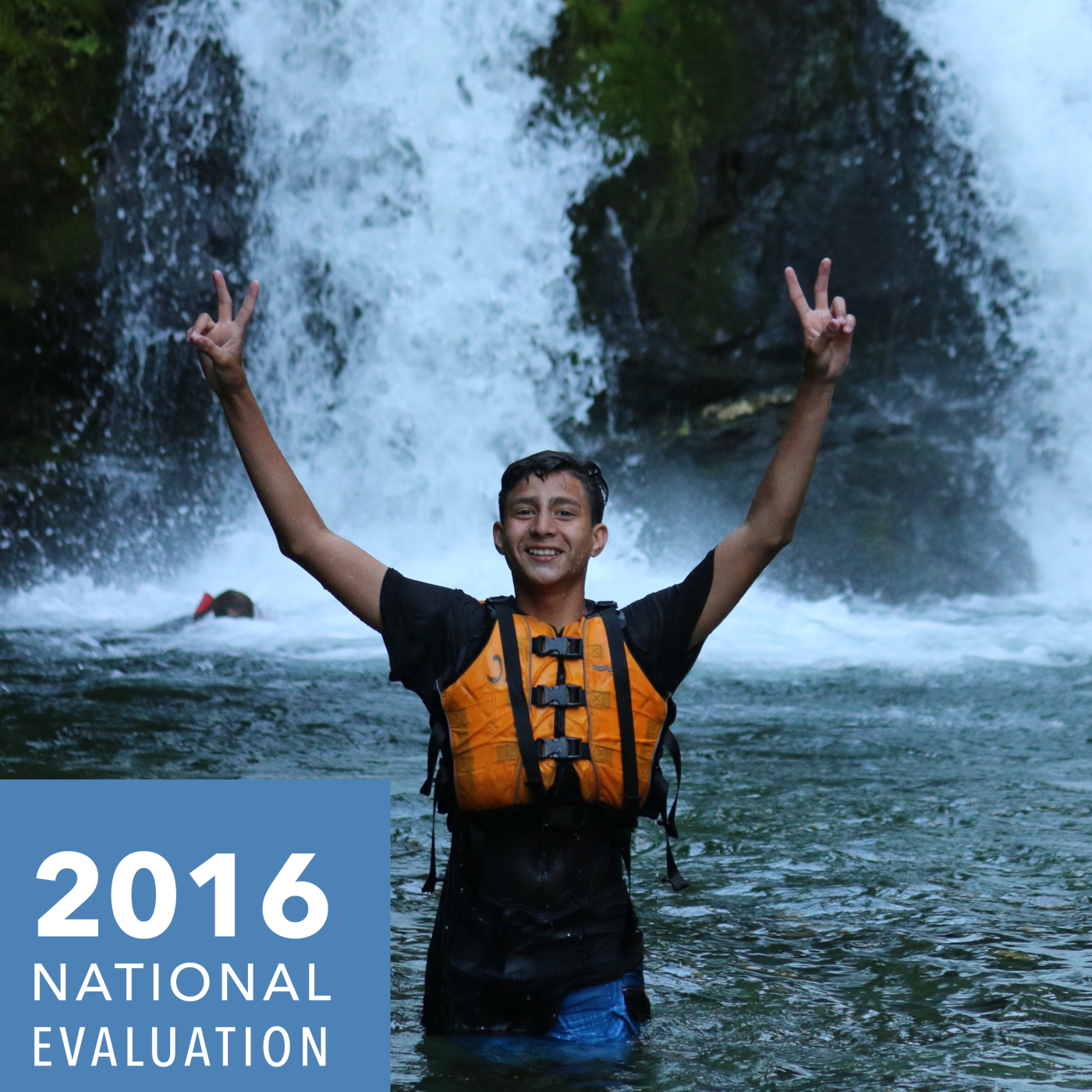A camper in front of a waterfall grinning