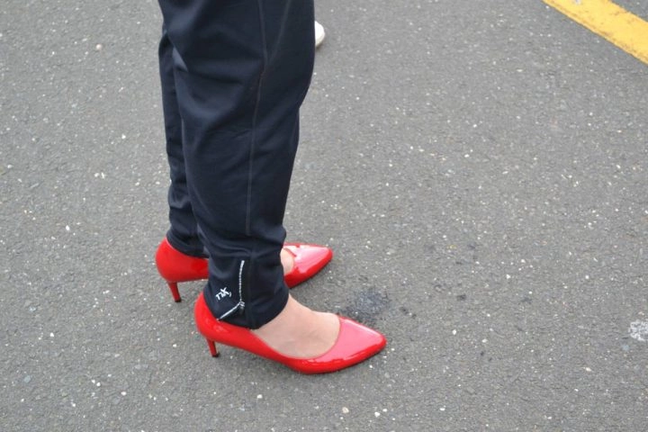 Person wearing red heels on road for Walk a Mile in Her Shoes event