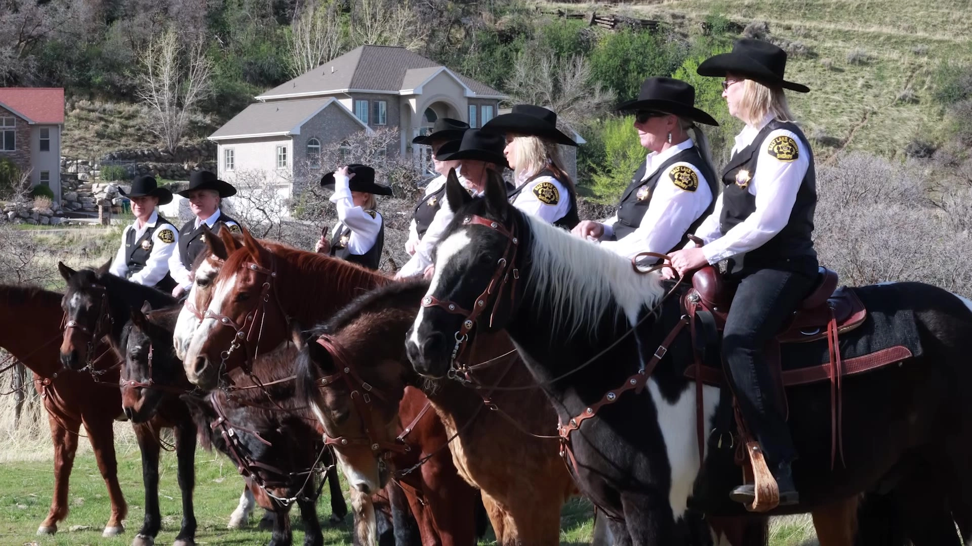 Law enforcement officers on horses wearing cowboy hats